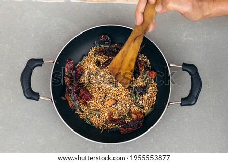 Roasted spices in pan on table with woman hand