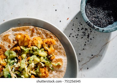 Roasted, Spicy Cauliflower Taco With Creamy Asian Slaw On Gray Plate With Black Sesame Seeds, Gochujang And Spicy Slaw In The Background.