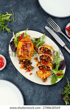 Roasted stuffed squid cut into thick slices and served on a white plate with sauteed vegetables.