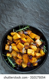 Roasted Sweet Potato With Red Onion And Rosemary.  Black Dish, Overhead View, Over Dark Slate.