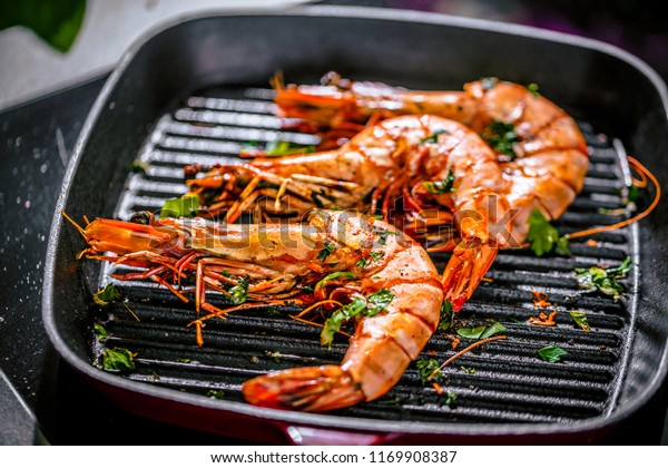 \
Roasted tiger prawns in iron grilling pan with\
 lemon, black background, top\
view