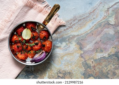 Roasted tomatoes with onion and thyme in a pan. Top view with copy space. Rustic food photography.