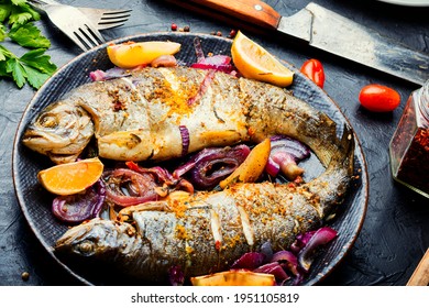 Roasted trout with lemon and onion on plate