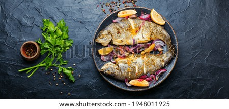 Roasted trout with lemon and onion on plate.Grilled trout