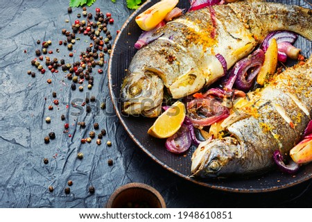 Roasted trout with lemon and onion on plate.Grilled trout