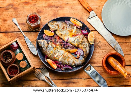Roasted trout with lemon and onion on rustic wooden background