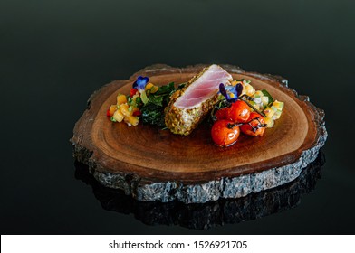 Roasted Tuna Steaks Crusted With Herbs And Grilled Vegetable And Mango Salsa On Wood Plate Isolated On Black Background