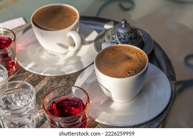 Roasted Turkish coffee. Pouring of hot coffee from cezve into cup on table.