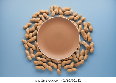 Roasted Unpeeled Peanuts In Shell In Beige Ceramic Plate Isolated On Blue Background. Food, Ingredients, Organic Vegetarian Protein, Healthy And Dietary Nutrition Concept. Top View With Copy Space.