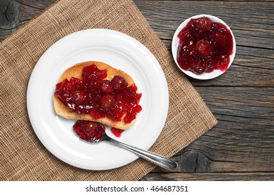 Roasted White Bread With Cherry Jam In Plate On Rustic Wooden Table, Top View