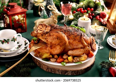 Roasted whole chicken with potatoes, mushrooms, tomatoes and garlic on Christmas table with festive decorations and green tablecloth - Shutterstock ID 2069738525