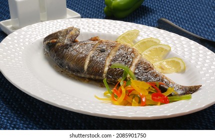 Roasted Whole Fish Seafood Served On White Plate Lemon Slices Capsicum Salt And Pepper Restaurant Table 