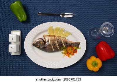 Roasted Whole Fish Seafood Served On White Plate Lemon Slices Capsicum Salt And Pepper Restaurant Table 