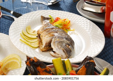 Roasted Whole Fish Seafood Served On White Plate Lemon Slices Capsicum Salt And Pepper Restaurant Table 