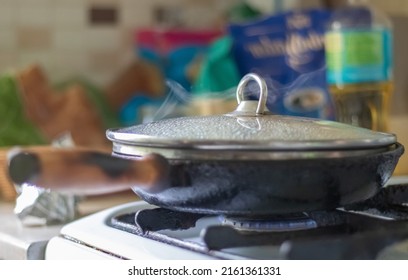 Roasting Fresh Potatoes In A Cast Iron Skillet With Sunflower Oil. A View Of A Stovetop With A Frying Pan Filled With Golden Fried Potatoes In A Real Kitchen. Food Cooked In A Homemade Frying Pan