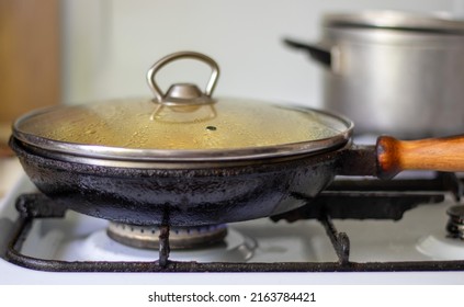 Roasting Fresh Potatoes In A Cast Iron Skillet With Sunflower Oil. A View Of A Stovetop With A Frying Pan Filled With Golden Fried Potatoes In A Real Kitchen. Food Cooked In A Homemade Frying Pan