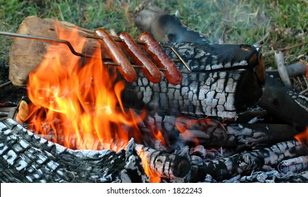 Roasting Hotdogs And Sausage Over Campfire