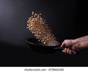 Roasting Peanuts, Male Hand Tossing Peanuts In A Frying Pan On Black Background, Close Up.