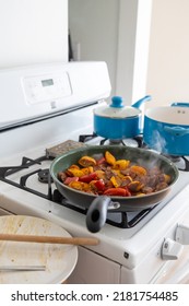 Roasting Peppers And Zucchini Vegetables On Non-stick Pan On White Stovetop While Cooking Two Other Items On Blue Pans- Healthy Meal Home Cooking Concept