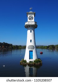 Roath Park Lake In Cardiff On A Summer Day With Lighthouse Clocktower Memorial To Those Lost On Scott's Terra Nova Expedition To Antartica In Foreground With Clear Blue Sky And A Single Paddle Boat II