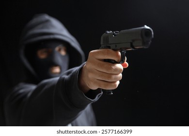 Robber with balaclava holding gun, ready to shoot.  Armed hooded killer Weapon, crime concept