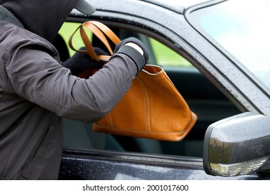 Robber breaking a car's windows to steal a woman bag.