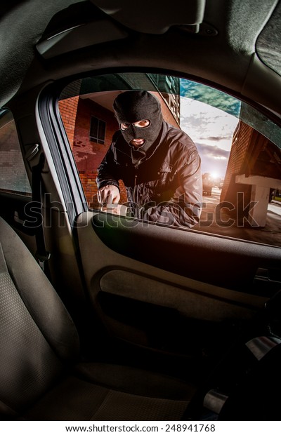 Robber and the car thief in a mask opens the\
door of the car and hijacks the\
car.