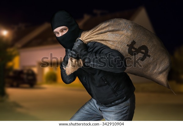 Robber is running away and carying full bag of\
money at night.