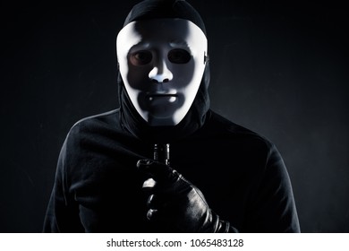 Robber in white mask holding flashlight - Shutterstock ID 1065483128