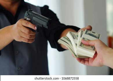 Robbery with gun's. Gun and money in a hands. Bank robbery, Man carrying a gun to rob the bank note. To threaten with the man. A murderer attacking holding gun kidnapping business young person.