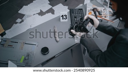 Robbery or murder case: Top view on female criminalist taking photos of knife with professional camera. Numbered marker stands next to murder weapon evidence. Forensic scientist works at crime scene