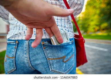 Robbery on city street. Thief steal tourist cash. Hand takes money from the back pocket of the jeans. Pickpocket rob a woman. Criminal in the city. Thieves use sneaky tricks to steal  money.