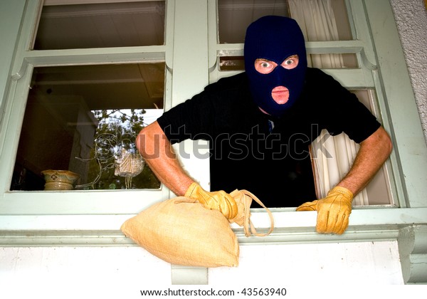 A burglar robbing a\
house wearing a\
balaclava.