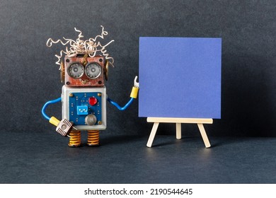 The robot and blue paper placard set on wooden easel. copy space for text. Black background. Gallery frame invitation card concept, empty frame mockup, copy space canvas. - Shutterstock ID 2190544645