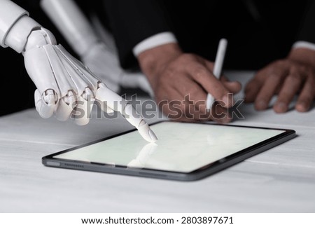 Robot hand and human hand working together on a digital tablet.