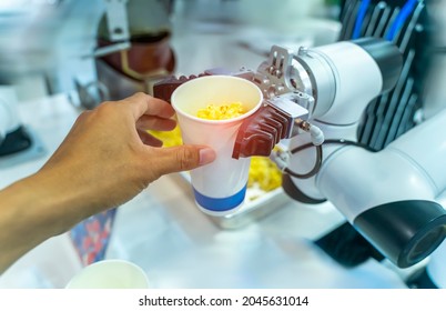 robot hand taking a bucket of popcorn to human hand