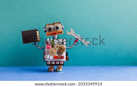 Robot handyman memory flash card hand wrench. Fixing maintenance concept. Creative design toy, cogs wheels gears silver metallic body. Green wall, blue floor background. Copy space.