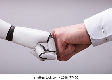 Robot And Human Hand Making Fist Bump On Grey Background