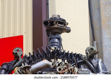 A robot made of car parts on the street in front of an auto parts store. - Shutterstock ID 2188970577