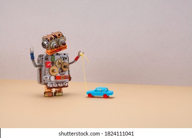 Robot plays with a vintage toy car. Gray beige background, copy space