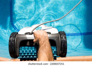 robot pool cleaner Pool maintenance with automatic robot. Cleaning the bottom of the pool and walls with a submersible robot. . maintenance worker putting the cleaner robot into the pool water - Shutterstock ID 2200037251