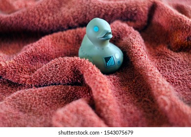            Robot Rubber Ducky Setting On A  Fluffy Maroon Towel                 