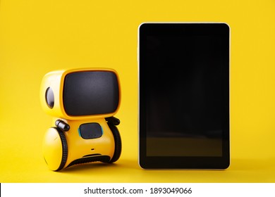 Robot Toy And Smart Phone On Bright Yellow Background. Tech Gifts For Educational. Chatbot Concept. Copy Space