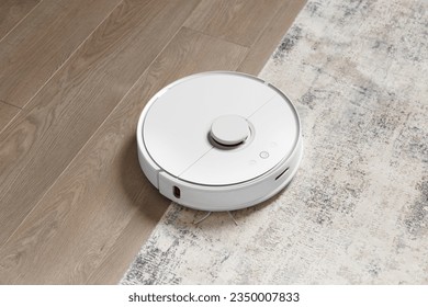 Robot vacuum cleaner on the carpet and on the laminate removes dust. The concept of a smart home, wireless cleaning with a smart vacuum cleaner of any surfaces. - Powered by Shutterstock