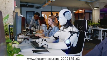 Robot working at computer among people. Maschine typing on keyboard in office. IT team of future. Futuristic worker. Humanoid work at call center. Support job. Selling concept. Technologies. Foto d'archivio © 