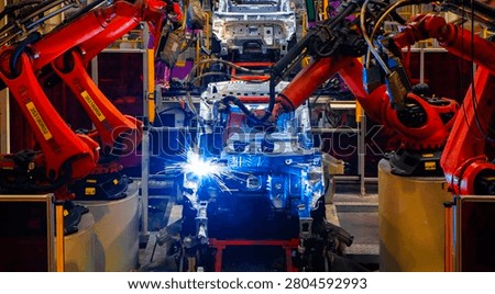 Robotic arms are welding points on the car body on an automated production line.