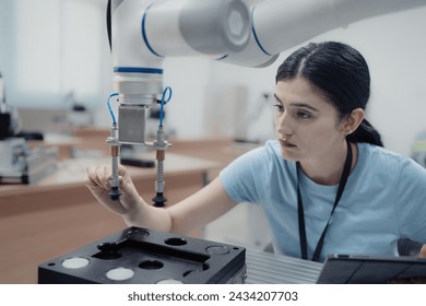 Robotic development engineer working robot arm connection and control at electronic futuristic science laboratory. Female technician learning smart innovation machine in automated engineering academy