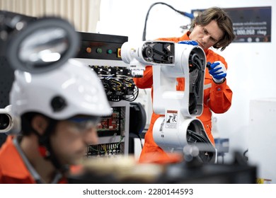 Robotic engineer examining robot power gear machine for repairing service. Modern technology technician working on hardware maintenance to repair steel and metal part of industrial automated equipment
