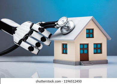 Robotic Hand Examining House Model With Stethoscope On Reflective Desk - Powered by Shutterstock