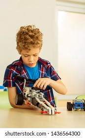 Robotic Hobby. Serious Cute Boy Holding A Car While Enjoying His Favourite Hobby